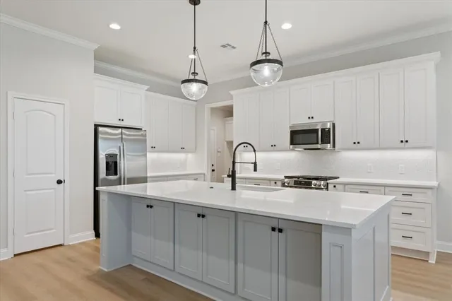 a kitchen with stainless steel appliances a stove a sink and white cabinets