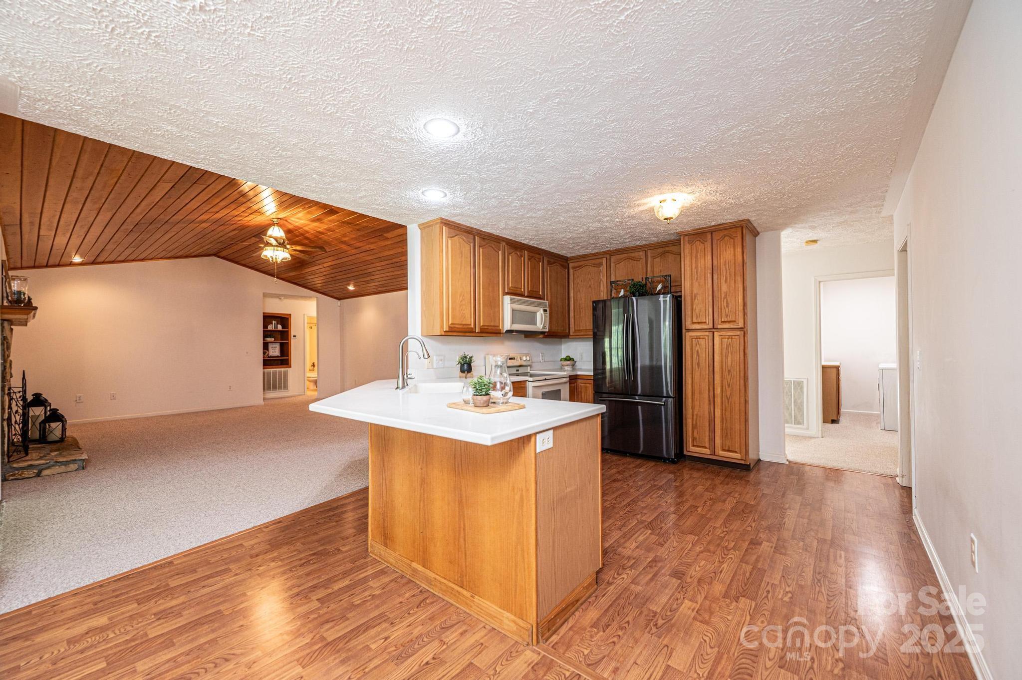 227 Robert Keever Road Stanley, NC 28164 - Photo 24 of 45 a kitchen with stainless steel appliances granite countertop a refrigerator a sink dishwasher a stove and white countertops with wooden floor