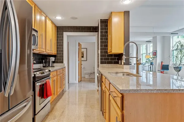 a kitchen with stainless steel appliances granite countertop a stove a sink and a refrigerator
