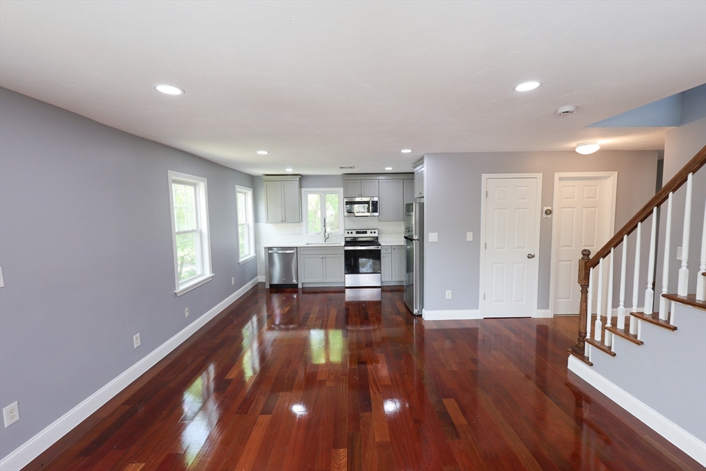 a view of a living room with wooden floor and a kitchen