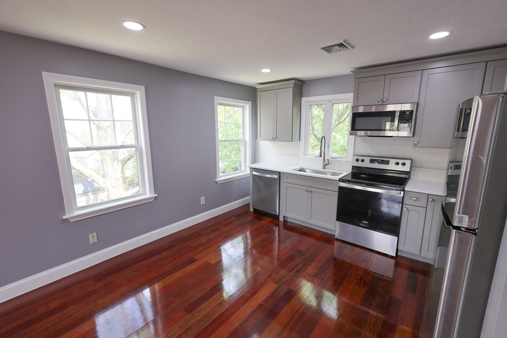 70 Mt Hope Street, Unit 2 Boston, MA 02131 - Photo 4 of 19 a kitchen with granite countertop stainless steel appliances a stove a sink a refrigerator cabinets and a window