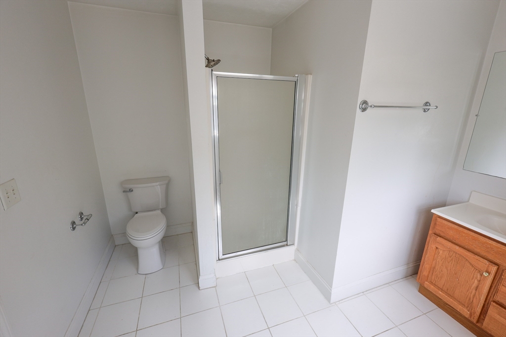 70 Mt Hope Street, Unit 2 Boston, MA 02131 - Photo 8 of 19 a bathroom with a granite countertop toilet and a sink