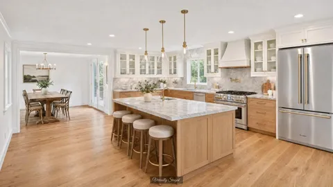 a kitchen with kitchen island a stove a refrigerator a dining table and chairs with wooden floor