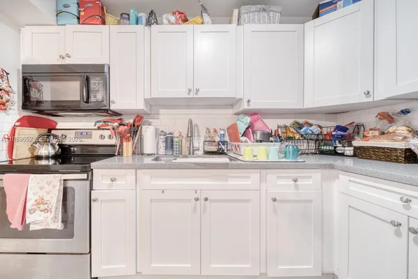 a kitchen with white cabinets and sink