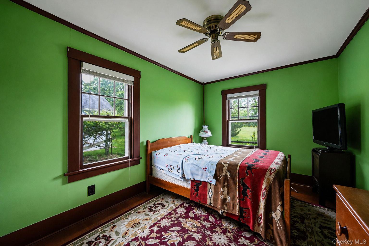 1055 Oregon Road Mattituck, NY 11952 - Photo 23 of 33 Room featuring two windows with dark wood trim, and a ceiling fan with light-colored blades