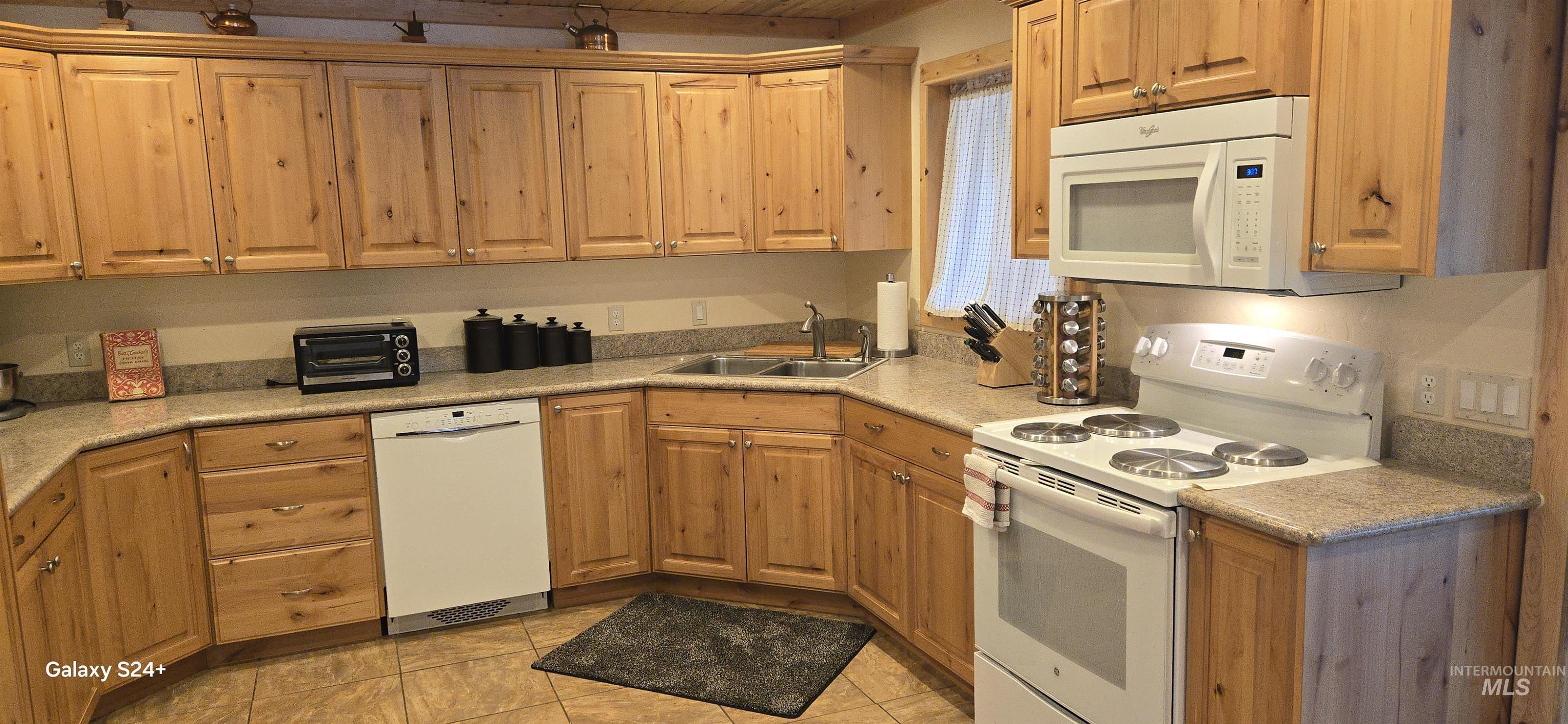4250 American River Road Elk City, ID 83525 - Photo 16 of 28 Kitchen featuring white appliances, light tile patterned floors, and wood finish cabinetry