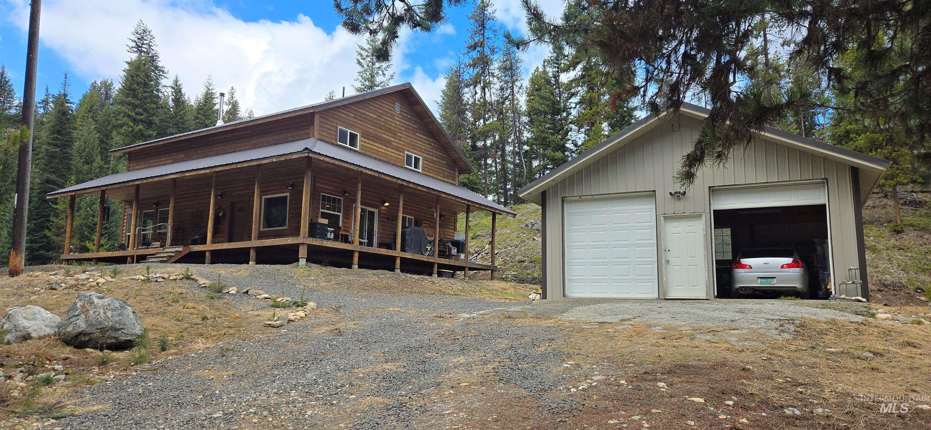 4250 American River Road Elk City, ID 83525 - Photo 2 of 28 View of home's exterior featuring a porch, a detached garage, an outbuilding, and a metal roof