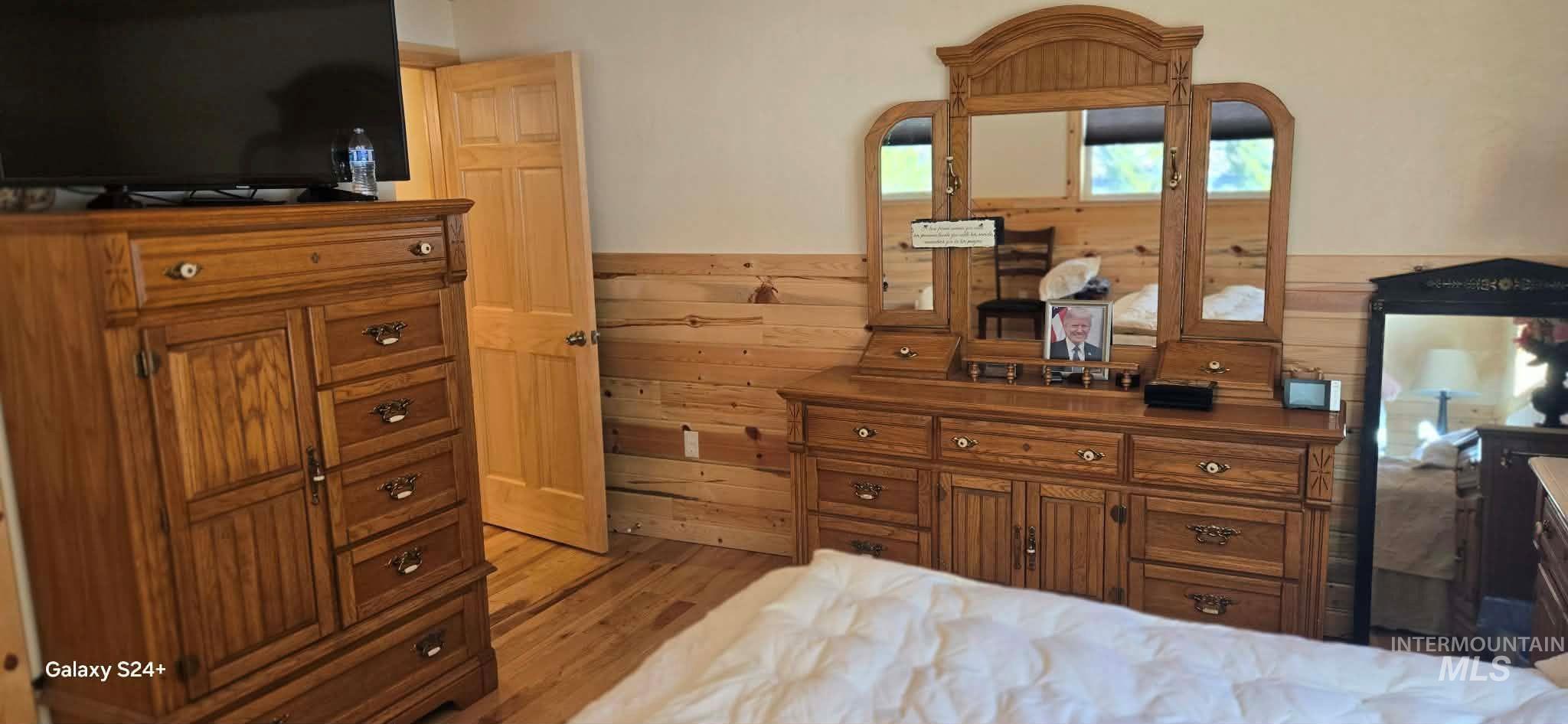 4250 American River Road Elk City, ID 83525 - Photo 21 of 28 Bedroom featuring a wainscoted wall, wood walls, and light wood-style flooring