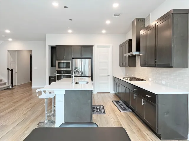 a large kitchen with stainless steel appliances kitchen island granite countertop a refrigerator and a stove top oven