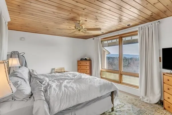 a bedroom with a large bed and a flat tv screen on dresser