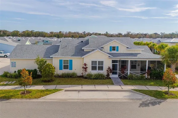 a view of a white house next to a yard and potted plants