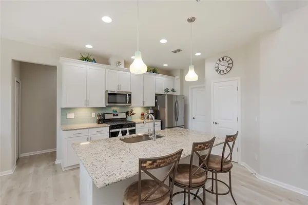 a kitchen with stainless steel appliances granite countertop a sink a stove a refrigerator with white cabinets and granite countertops