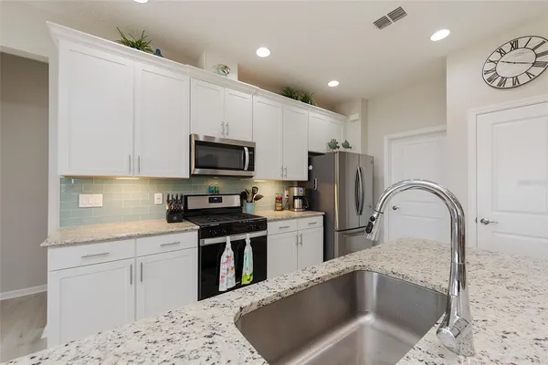 a kitchen with stainless steel appliances granite countertop a refrigerator stove a sink and dishwasher with wooden floor