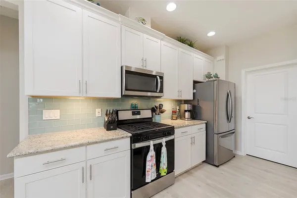 a kitchen with white cabinets and stainless steel appliances