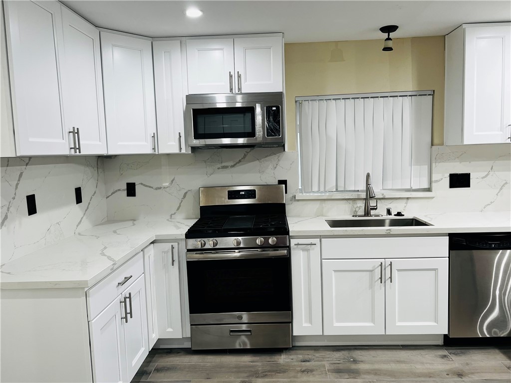 12771 Ponderosa Ranch Road Victorville, CA 92392 - Photo 7 of 23 a kitchen with white cabinets and black appliances