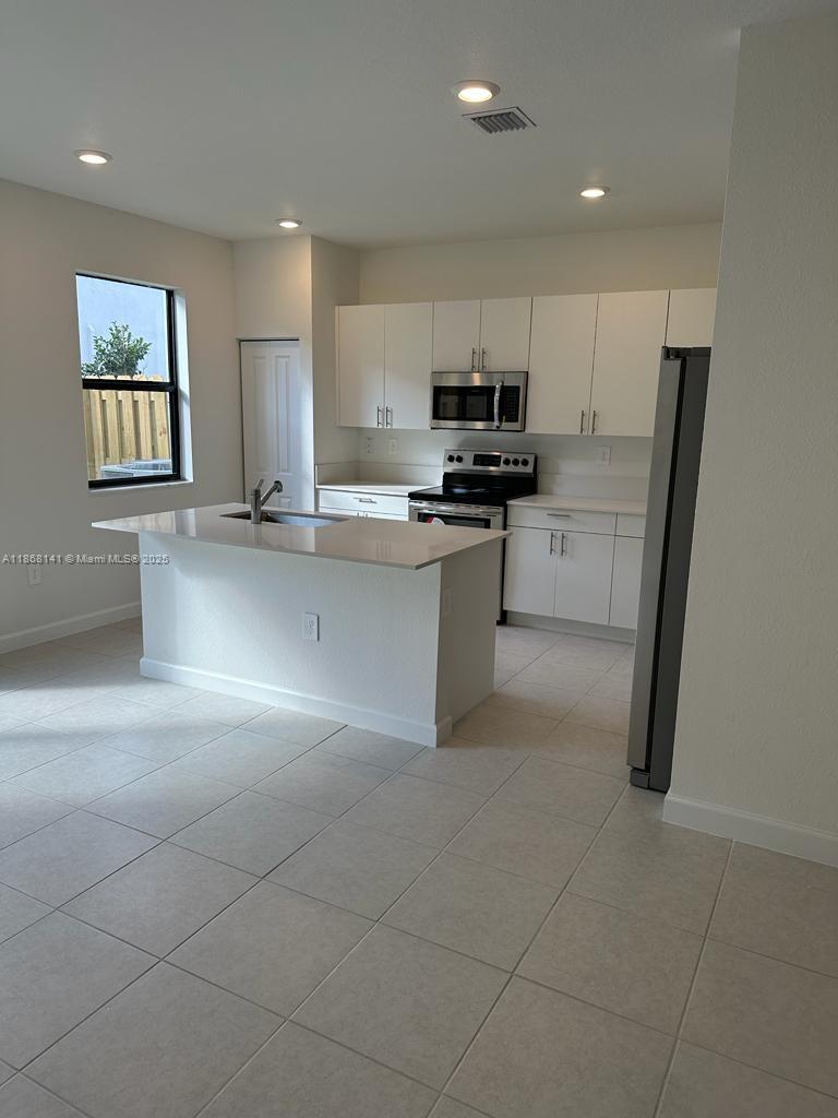 11926 Southwest 245 Terrace Homestead, FL 33032 - Photo 11 of 43 a kitchen with stainless steel appliances a refrigerator sink and microwave