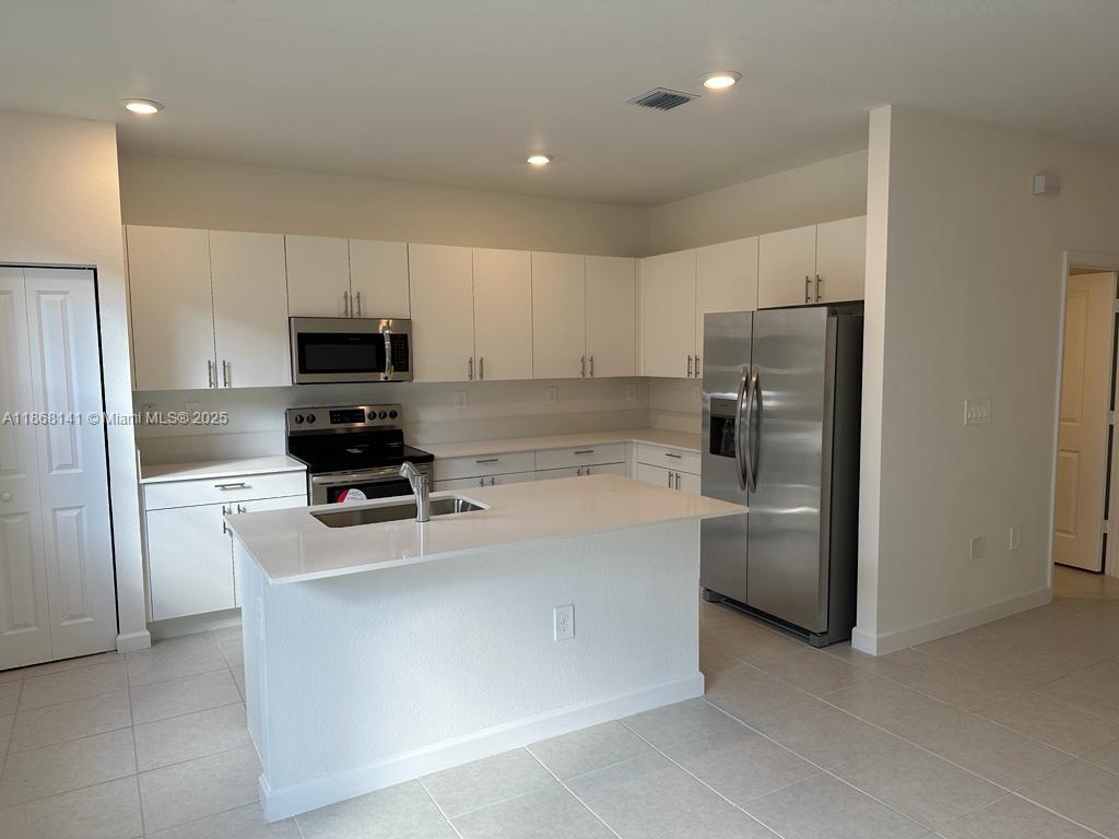 11926 Southwest 245 Terrace Homestead, FL 33032 - Photo 16 of 43 a kitchen with stainless steel appliances a refrigerator a stove a sink and white cabinets