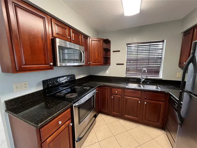 a kitchen with granite countertop cabinets stove top oven and sink