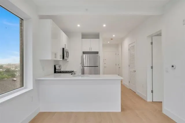 a view of kitchen with granite countertop cabinets and refrigerator