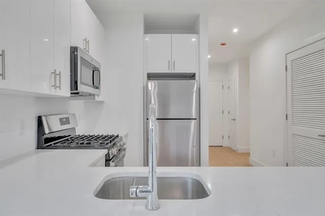 a kitchen with stainless steel appliances granite countertop a sink and a refrigerator
