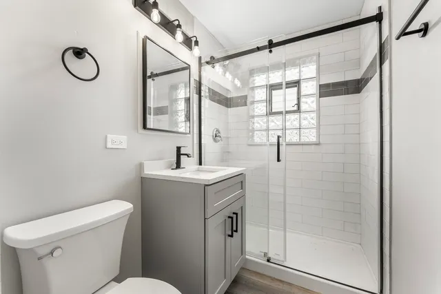 a bathroom with a sink a mirror a toilet and shower