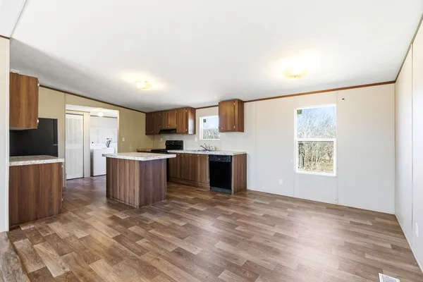 a kitchen with kitchen island granite countertop a stove top oven a sink dishwasher and a refrigerator with wooden floor