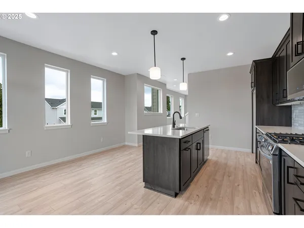 a kitchen with stainless steel appliances granite countertop a sink a stove and a wooden floors