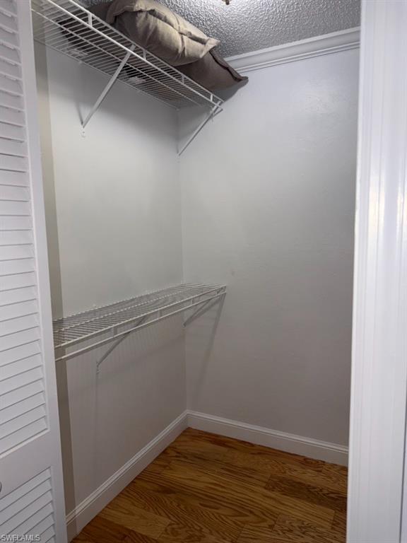 5395 Treetops Drive, Unit I Naples, FL 34113 - Photo 11 of 18 Walk-in closet featuring wood-finish flooring, white wire shelving, white walls, and crown molding