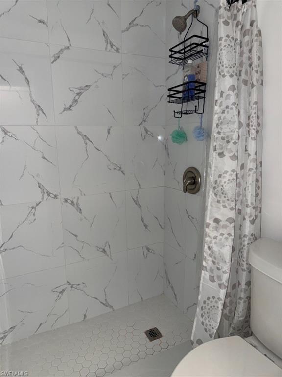 5395 Treetops Drive, Unit I Naples, FL 34113 - Photo 13 of 18 Shower enclosure featuring large format white tile walls with gray veining and a hexagonal mosaic tile floor