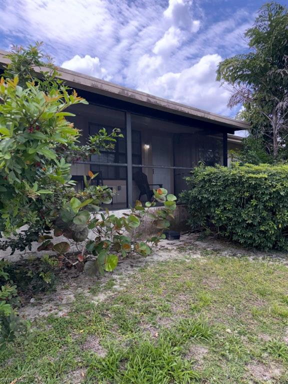 5395 Treetops Drive, Unit I Naples, FL 34113 - Photo 2 of 18 Screened patio with a covered overhang, surrounded by mature landscaping and a grassy area