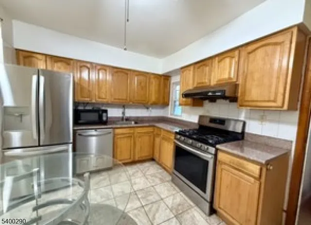a kitchen with stainless steel appliances granite countertop a stove a sink dishwasher a refrigerator and cabinets with wooden floor