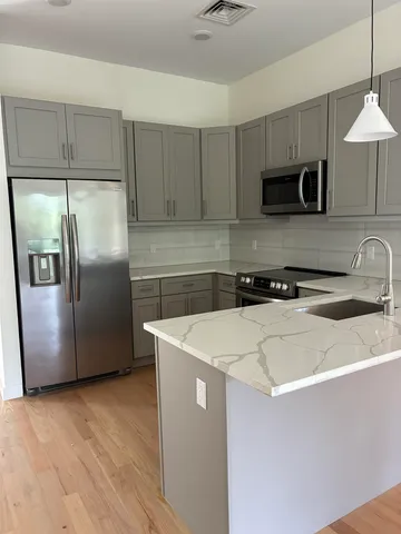 a kitchen with stainless steel appliances a refrigerator a sink a stove a microwave and wooden floor