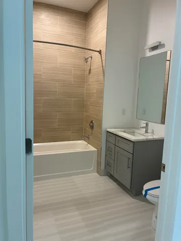 a bathroom with a bathtub shower sink vanity and toilet