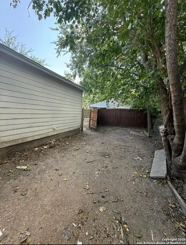 a backyard of a house with lawn chairs and wooden fence
