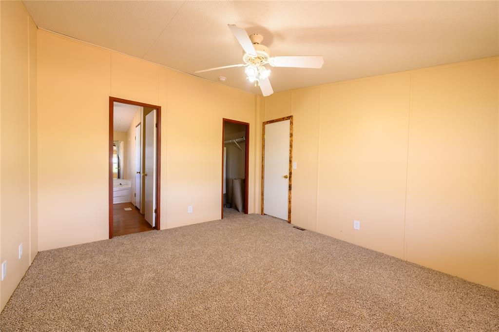 383 Soaring Eagle Trail Wichita Falls, TX 76310 - Photo 15 of 36 Unfurnished bedroom featuring carpet floors, a walk in closet, a ceiling fan, and ensuite bathroom