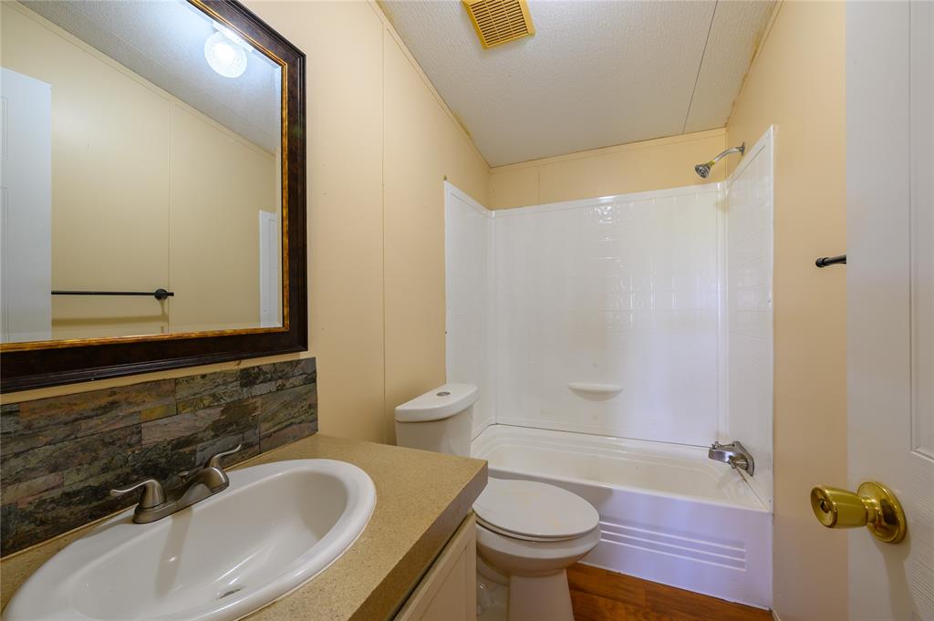 383 Soaring Eagle Trail Wichita Falls, TX 76310 - Photo 18 of 36 Bathroom with vanity, shower combination, decorative backsplash, a textured ceiling, and dark wood finished floors