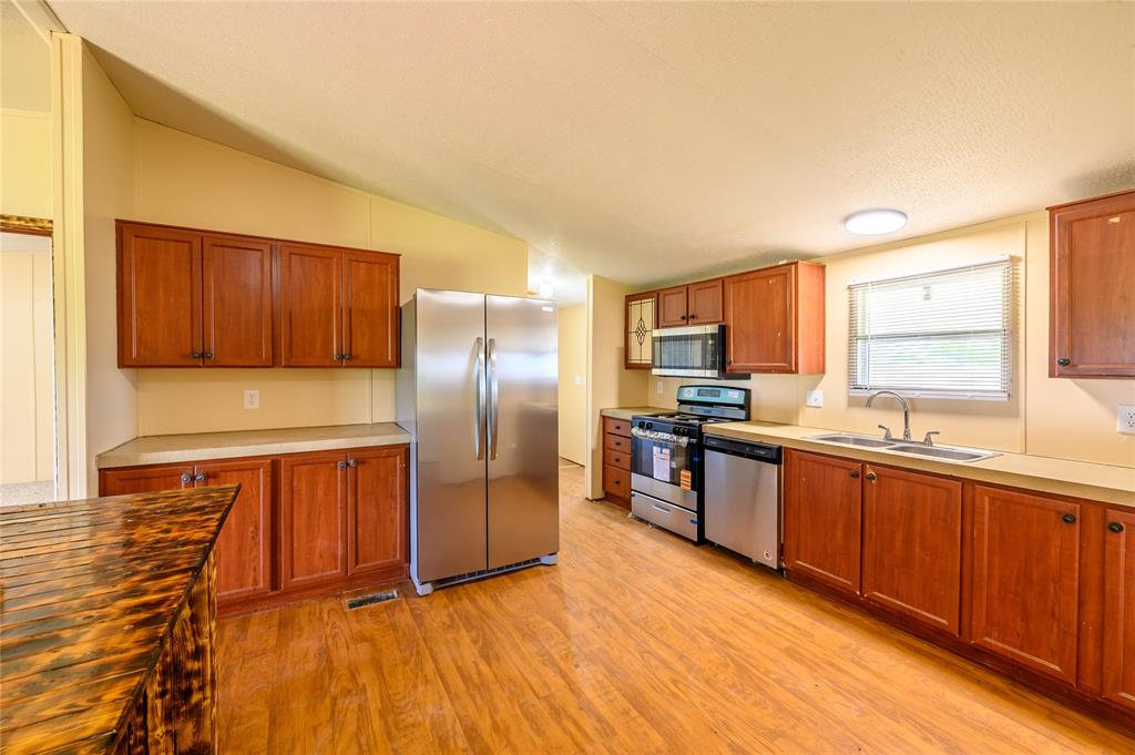 383 Soaring Eagle Trail Wichita Falls, TX 76310 - Photo 7 of 36 Kitchen featuring stainless steel appliances, wood finish cabinetry, light wood-type flooring, vaulted ceiling, and wooden counters