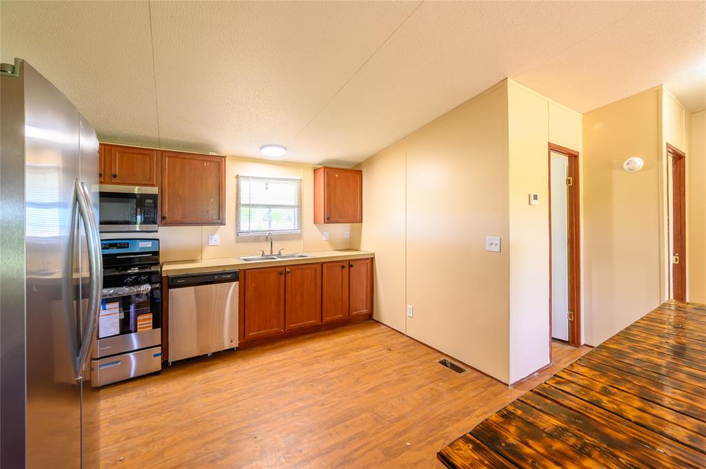 383 Soaring Eagle Trail Wichita Falls, TX 76310 - Photo 8 of 36 Kitchen featuring stainless steel appliances, wood finish cabinets, light wood finished floors, and a textured ceiling
