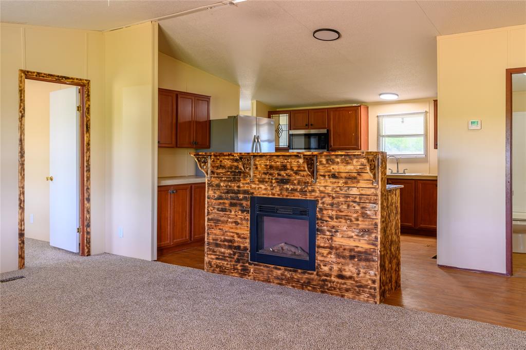 383 Soaring Eagle Trail Wichita Falls, TX 76310 - Photo 9 of 36 Unfurnished living room featuring a glass covered fireplace, dark carpet, and lofted ceiling
