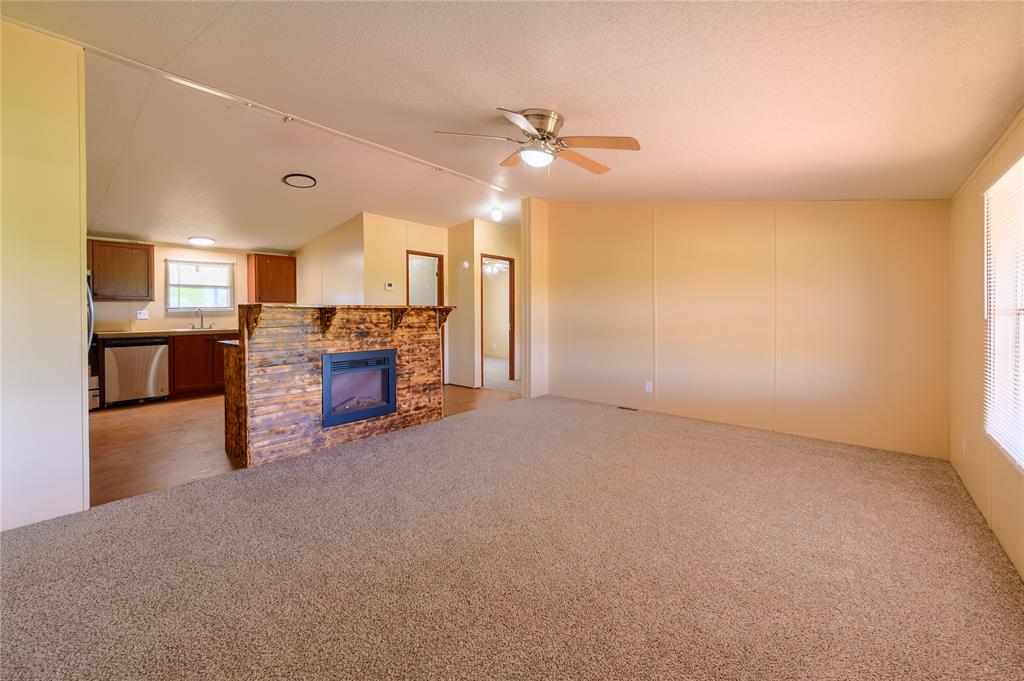 383 Soaring Eagle Trail Wichita Falls, TX 76310 - Photo 10 of 36 Unfurnished living room featuring light carpet, ceiling fan, and a fireplace