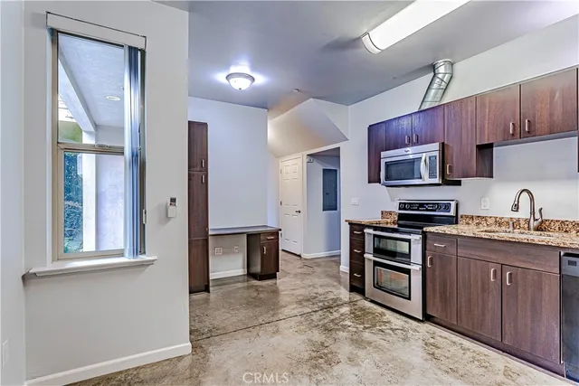 a kitchen with stainless steel appliances granite countertop a stove top oven a sink dishwasher a dining table and chairs with wooden floor