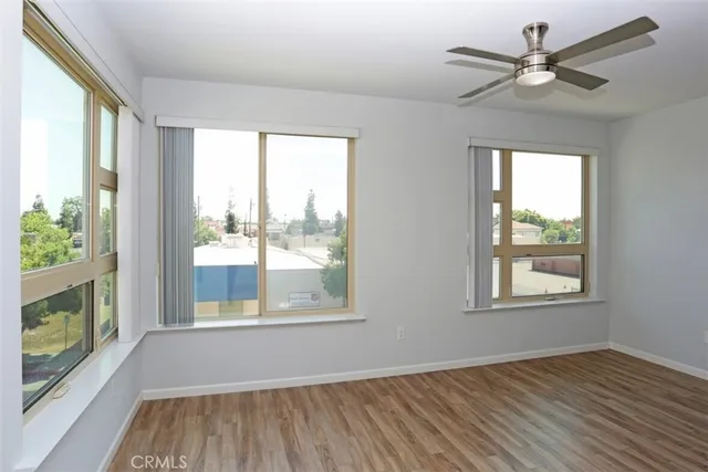 a view of an empty room with a window and wooden floor