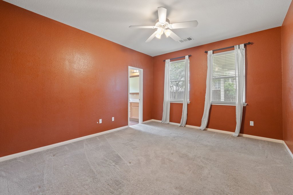 347 Spring Drive Kyle, TX 78640 - Photo 28 of 40 A well-lit bedroom features plush carpeting and a convenient ceiling fan for ultimate comfort.