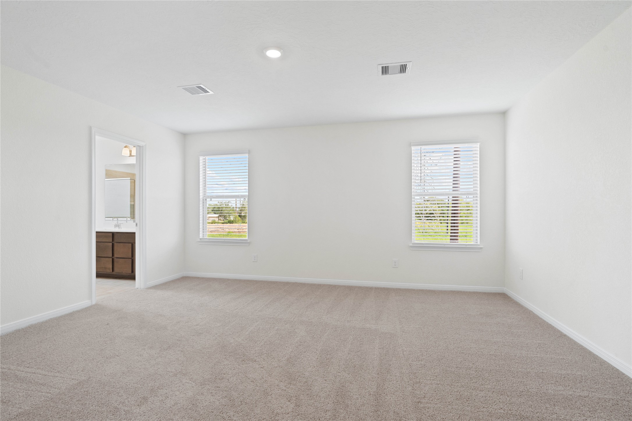 6403 Canby Court Rosharon, TX 77583 - Photo 12 of 23 Relax and unwind after a long day in this impressive primary suite! This generously sized room offers plush carpeting, warm-toned paint, high ceilings with recessed lighting, and large windows with privacy blinds for added comfort and tranquility.