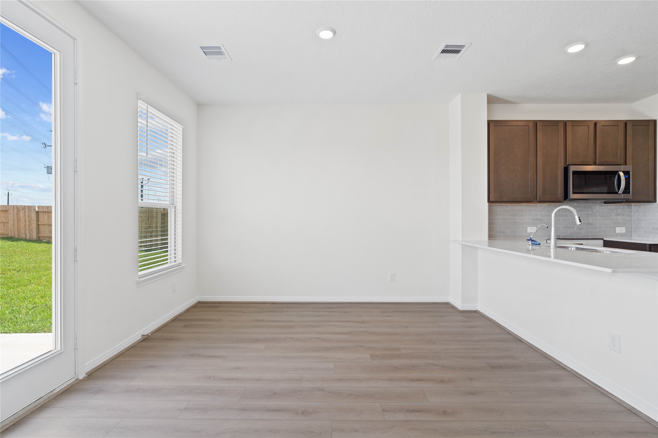 6403 Canby Court Rosharon, TX 77583 - Photo 7 of 23 Create lasting memories around the table with family and friends in this inviting dining room! It showcases high ceilings, large window with privacy blinds, vinyl plank flooring, access door to the backyard, and recessed lighting for a warm and welcoming atmosphere.