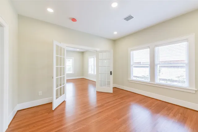 an empty room with wooden floor and windows