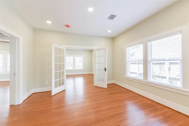 a view of empty room with wooden floor and fan