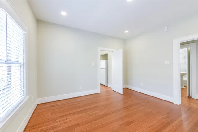 an empty room with wooden floor and windows