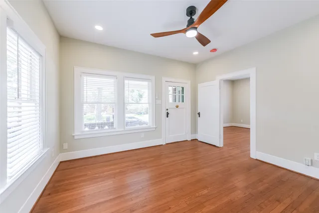 a view of an empty room with a window and wooden floor