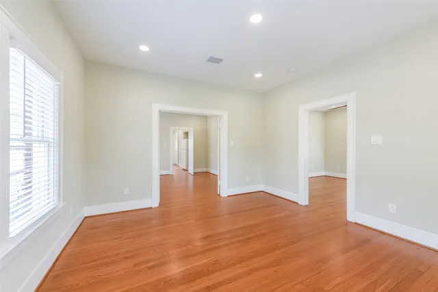 a view of an empty room with wooden floor and a window